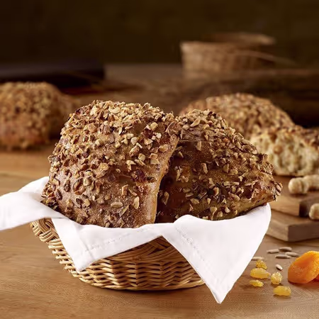 Marathonbrot mit Nusskruste im Korb neben Trockenfrüchten