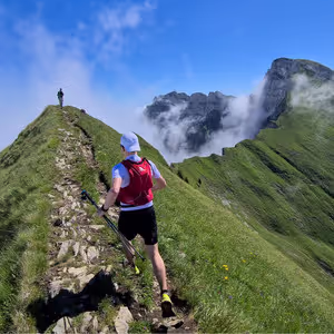 Läufer auf einem schmalen Grat über den Wolken